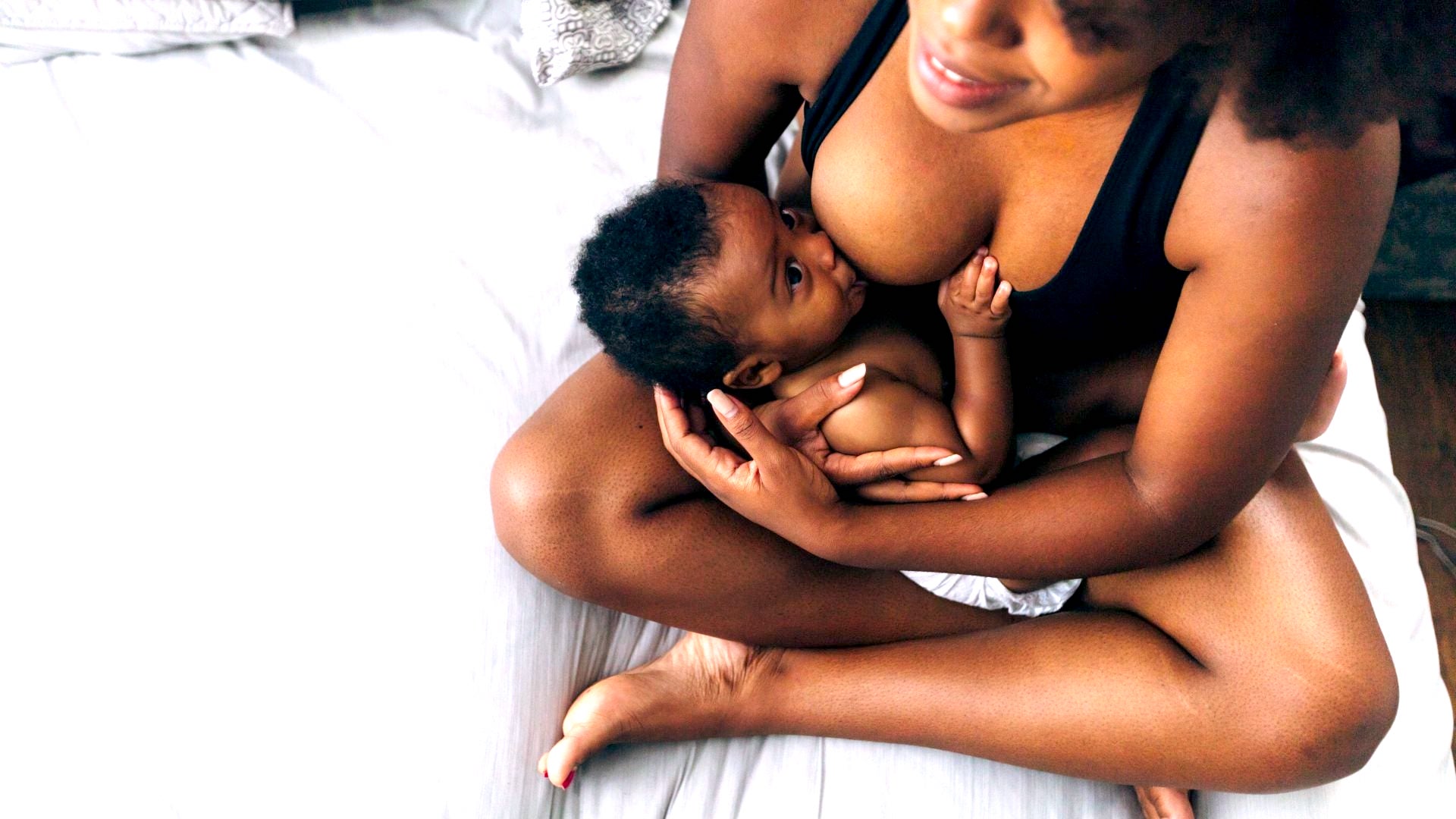 black mother breastfeeding her baby in bed